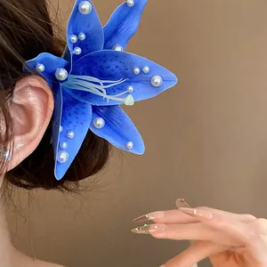 Macro view of blue fabric lily hair clip featuring elegant pearl embellishments on petals