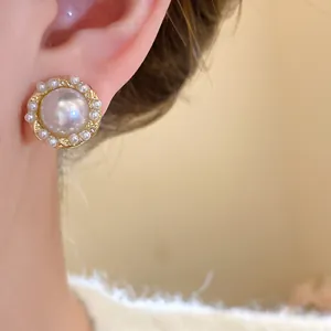 Elegant French vintage gold pearl stud earrings shown as a close-up on a model's ear.