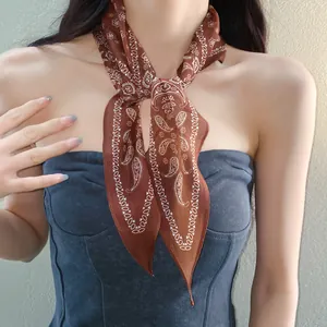 Gros plan d'un foulard en soie marron à motif cachemire porté comme accessoire de cou chic.