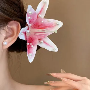 Elegant close-up of a pink fabric lily hair clip embellished with white pearls on a model