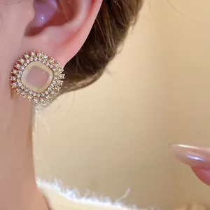 Close-up of vintage square stud earrings with shimmering rhinestones and a cat-eye stone.