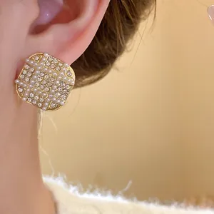 Close-up of French vintage square earrings with pearls and rhinestones on model's ear.