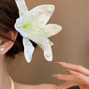 Detailed macro shot of a white fabric lily hair clip decorated with elegant pearls