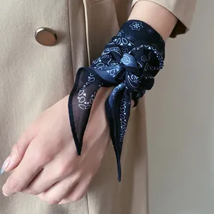Gros plan d'un foulard en soie à fleurs bleu marine noué au poignet d'une femme