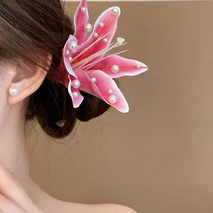 Side detail view of a sweet pink fabric lily hair clip with pearl accents worn on hair.
