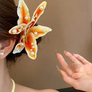 Detailed close-up of a vibrant orange lily hair clip embellished with elegant white pearls