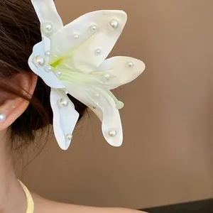 Close-up of elegant white fabric lily hair clip with pearl embellishments on hair