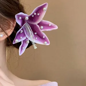 Close-up detail of purple fabric lily hair clip with white pearl accents on a model