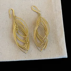 Macro view of elegant gold oval hollow layered dangle earrings with textured finish