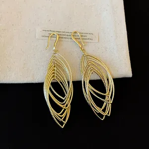 Detailed view of elegant gold hollow pleated elliptical ear hook earrings with a textured finish