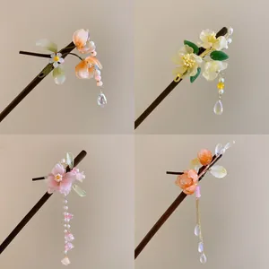Close-up of four floral hairpins with tassels in pink, orange, and yellow tones.