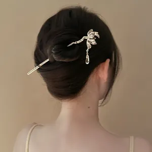 Elegant gold flower hair stick with tassel pendant worn in a refined traditional bun