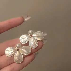 Macro detail of French vintage shell petal pearl earrings with pearlescent luster
