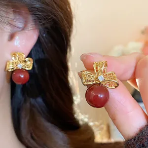 Detailed close-up of 18k gold plated vintage bow earrings with zircon and red pearl