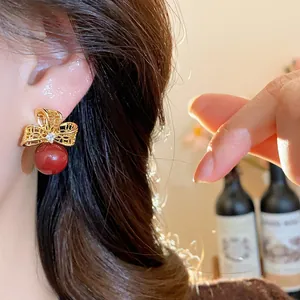 Close-up detail of vintage 18k gold plated zircon flower earrings with red pearl drop