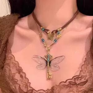 Close-up of vintage punk necklace with dragonfly wing key pendant and blue rhinestones