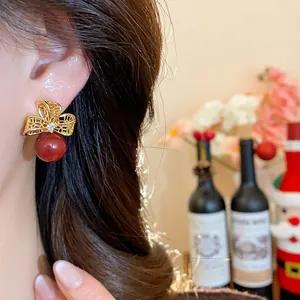 Detailed view of an 18k gold-plated zircon flower earring with a vibrant red bead.