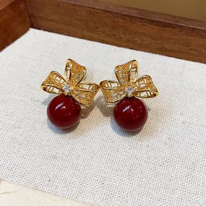 Close-up of retro 18k gold plated earrings with red pearls and zircon flower details