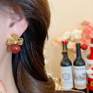 Detailed close-up showing vintage 18k gold plated bow earrings with red beads on an ear.