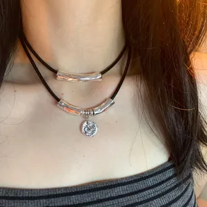 Minimalist double-layered silver choker necklace with black cord and embossed coin pendant.