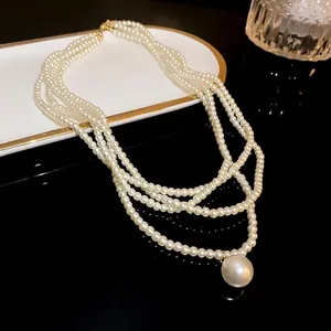 Elegant multi-strand pearl necklace featuring a large round pendant on dark surface