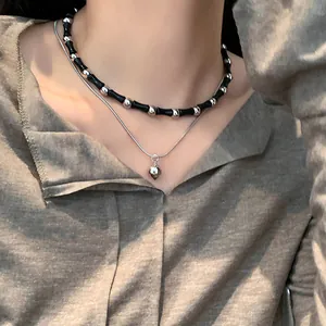Close-up of vintage punk double-layer necklace with black beads and heart pendant.
