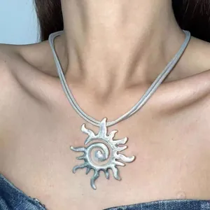Close-up detail of a vintage distressed silver sun pendant necklace on a female model