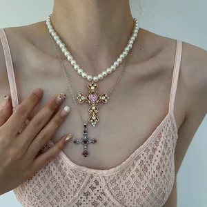 Detail of layered pearl and silver chain necklaces with ornate cross pendants.