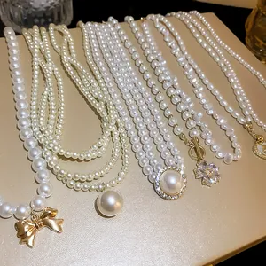 Close-up of various elegant pearl necklaces with gold-toned charms and flower pendants