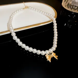 Close-up of elegant pearl necklace featuring a polished golden bow pendant.