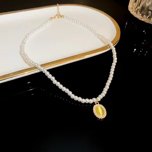 Elegant close-up of a pearl choker necklace featuring a light green cat eye stone pendant