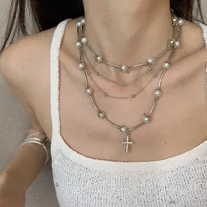Detail shot of vintage punk multi-layer metal necklace with pearls and cross pendant