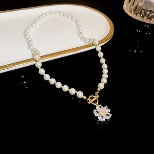Elegant close-up of a pearl necklace with rhinestone flower pendant and gold OT clasp