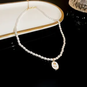 Elegant faux pearl necklace featuring an oval floral pendant on a minimalist reflective display