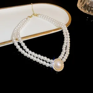 Detail of elegant double-strand pearl necklace with a round crystal-halo pendant.