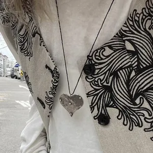 Detailed view of the distressed vintage silver heart pendant necklace on a black rope