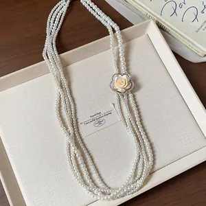 A detail view showing the elegant multi-strand pearl necklace with a rhinestone rose.