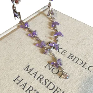 Exquisite necklace featuring purple glass butterfly pendants on a vintage book backdrop