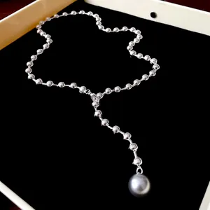 Vista detallada de un elegante collar de perlas con cuentas de metal y colgante gris