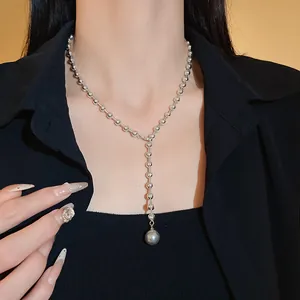 Vista detallada de collar en Y de bolas plateadas con perla gris en una modelo