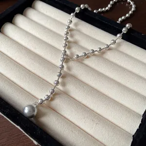 Primer plano detallado de un collar de cadena de bolas plata con perla gris.