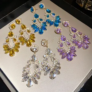 Close-up of luxury chandelier crystal earrings in yellow, blue, and purple colors.