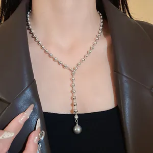 Detalle de un elegante collar de cuentas plateadas con colgante de perla gris en modelo