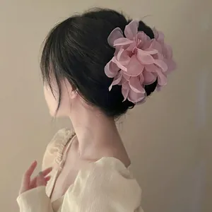 Elegant pink 3D fabric flower hair clip displayed on a soft and romantic updo bun