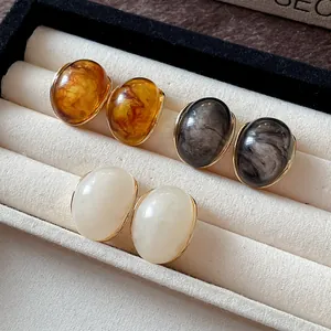 Detalle de pendientes de resina retro con textura de mármol en joyero