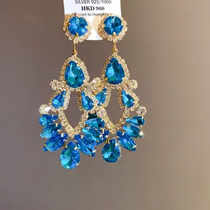 Detailed view of ornate blue crystal chandelier earrings in royal palace style.