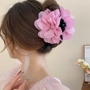 A detailed view of a pink 3D floral hair claw clip on a woman's stylish updo.