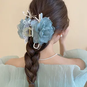 Detailed view of an elegant blue organza flower hair claw clip on a braided hairstyle.