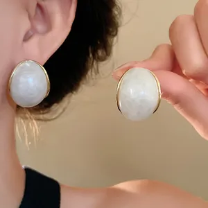 Primer plano de pendientes de resina vintage con diseño de mármol y borde dorado