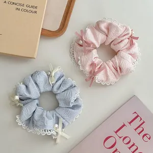 Detail view of pastel pink and blue scrunchies with lace trim, bows and small pearls